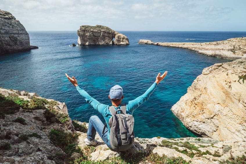 Traveler man feels free seeting on the rocky seaside of blue lagoon